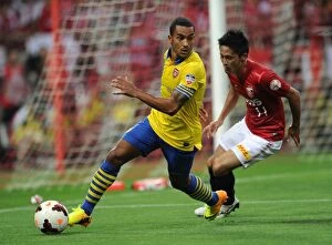Uwara Red Diamonds v Arsenal 2013-14 Collection: Theo Walcott vs. Kunimitsu Sekiguchi: A Battle for Ball Possession in Arsenal's 2013-14 Pre-Season